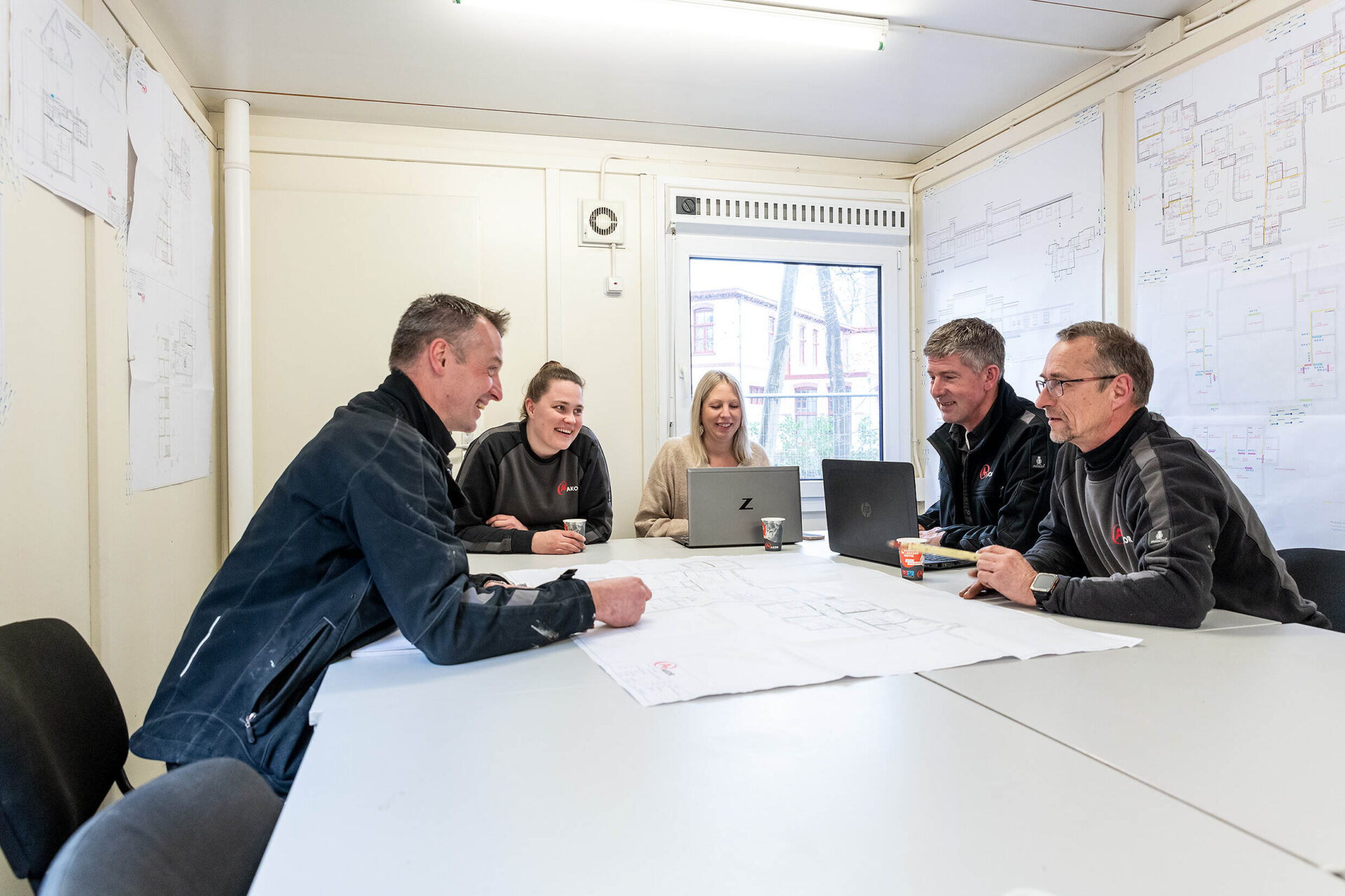 Uitvoeringsteam en opdrachtgever in bouwkeet tijdens bouwvergadering. Korte lijnen tijdens de uitvoering zorgen voor een eindresultaat war iedereen trots op kan zijn.