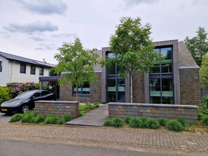 Minimalistische gevel met warme houtaccenten en robuuste leien bekleding. Deze woning in Schaarsbergen kreeg een complete transformatie met oog voor detail, materiaalgebruik en uitstraling. Een eigentijdse renovatie met karakter.